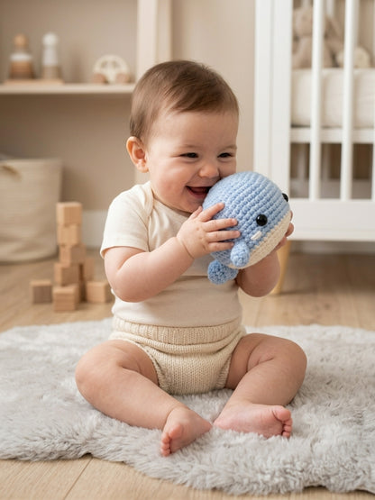Baby cuddling Bubbles the crochet whale in a cosy nursery – Bundle Company